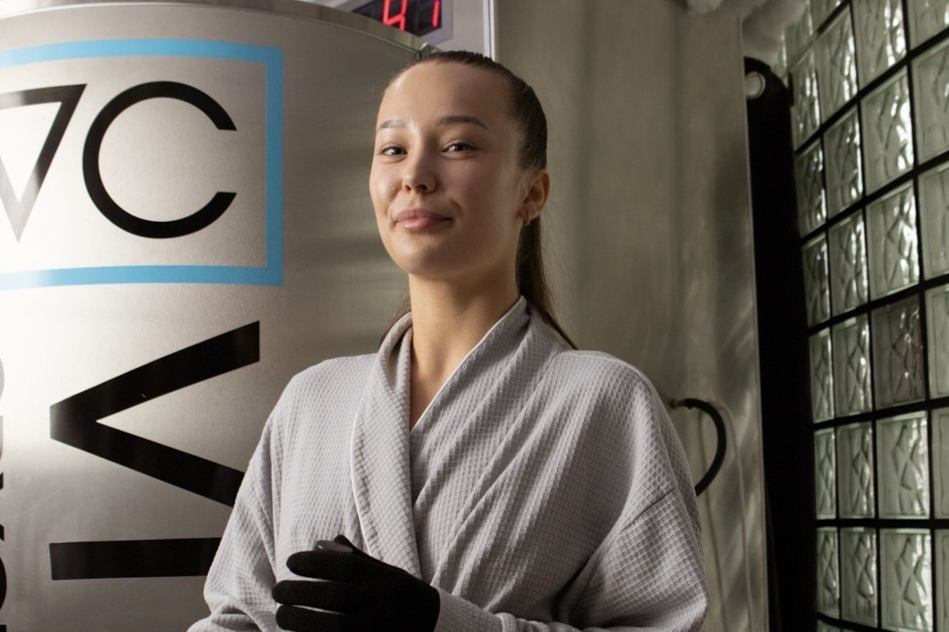 Client in a robe beside the cryotherapy chamber